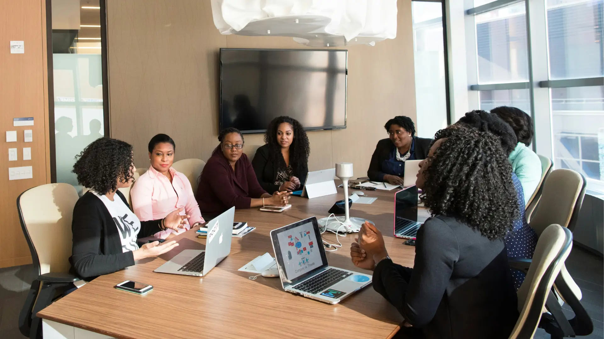 mulheres negras conversando em uma mesa de uma sala de reunião